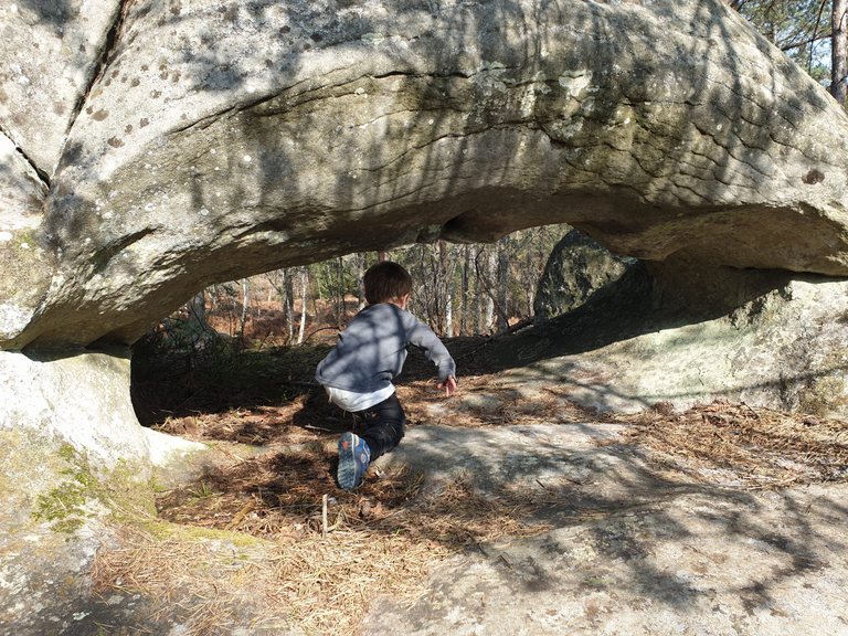 Child climbing under rock